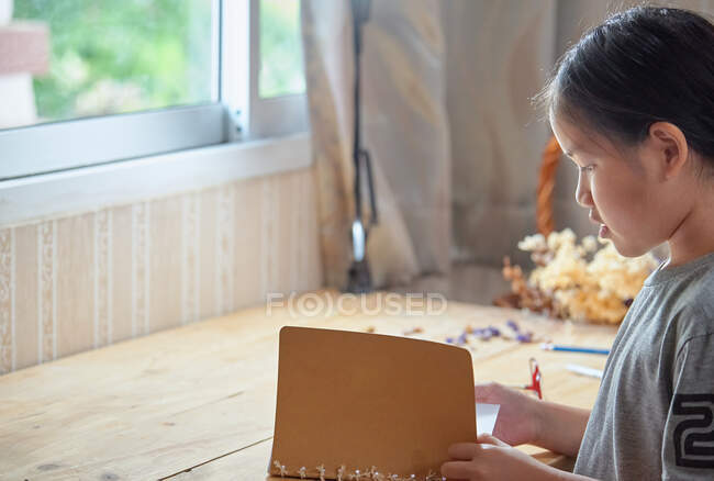 Девушка читает книгу на большом деревянном столе — стоковое фото