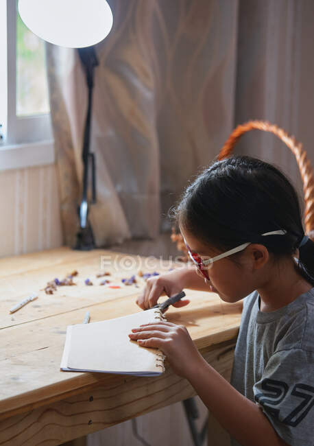 Uma menina cortando uma corda em seu trabalho de artesanato mão — Fotografia de Stock