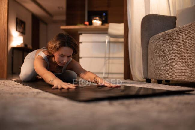 Молодая женщина делает Extended Childs позировать на мат во время занятий йогой у себя дома — стоковое фото