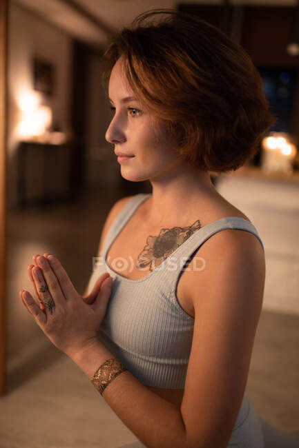 Seitenansicht einer Frau, die Hände umklammert und meditiert, während sie nachts Yoga praktiziert — Stockfoto