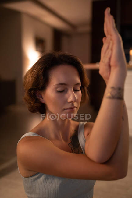 Jovem mulher fechando os olhos enquanto meditava com braços de águia enquanto praticava ioga — Fotografia de Stock