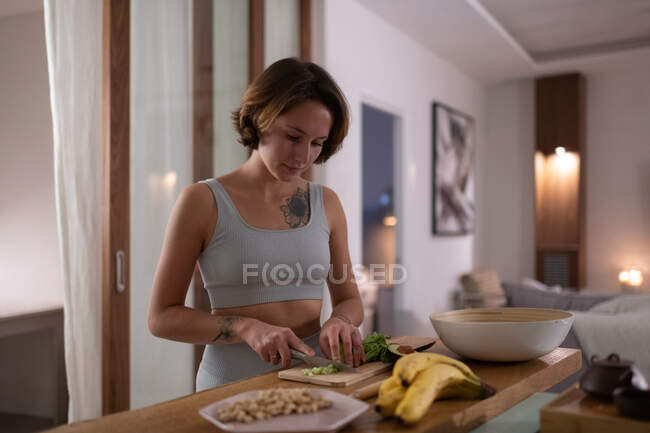 Alface corte feminino magro enquanto prepara salada vegan saudável para o jantar em casa — Fotografia de Stock