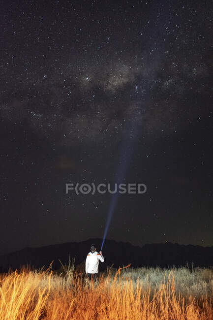 Joven en el campo observando la Vía Láctea con una linterna en hola - foto de stock
