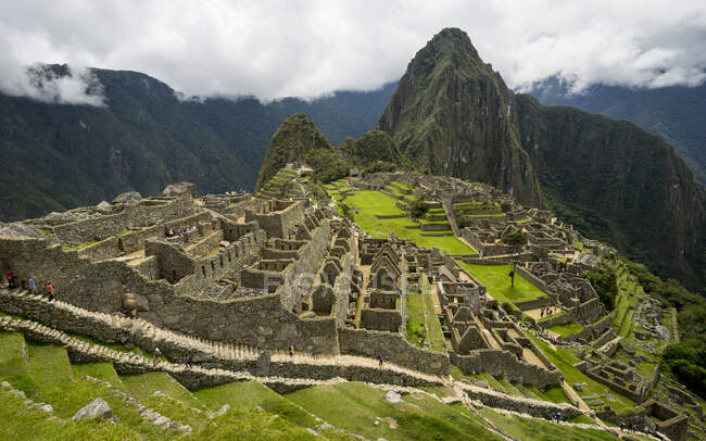 Machu picchu view with green grass and walking people — стоковое фото