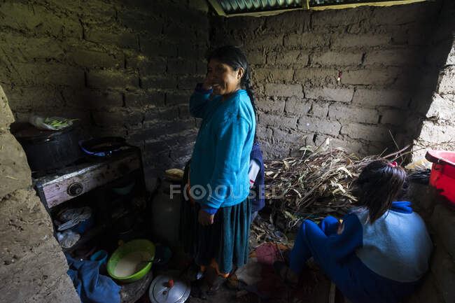Smiling woman standing in kitchen by daughter during homestay at Amantani Island, Peru — Stock Photo