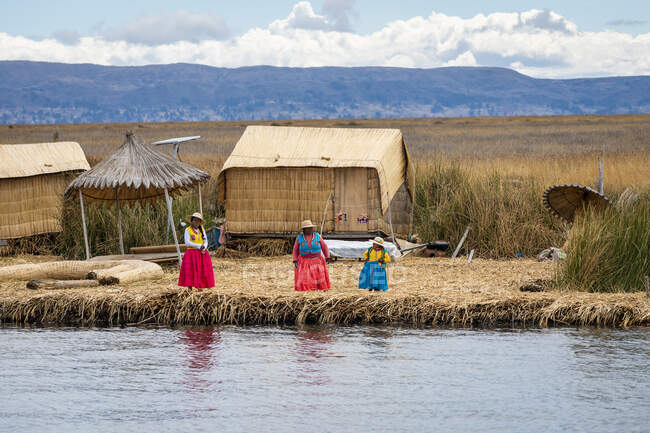 Três mulheres esperando para cumprimentar turistas que chegam às Ilhas Uros (Ilhas Reed), Lago Titicaca, Peru — Fotografia de Stock