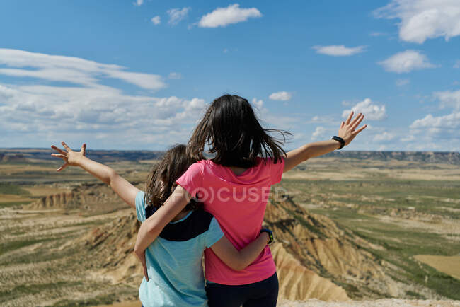 Kleine Schwestern in Sichtweite beobachten mit offenen Armen einen Wüstenberg im Nationalpark Bardenas Reales in Navarra, Spanien. Reisekonzept — Stockfoto