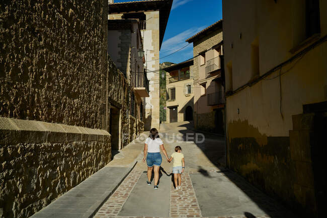 Madre e hija caminando en un callejón con casas antiguas en Mora - foto de stock