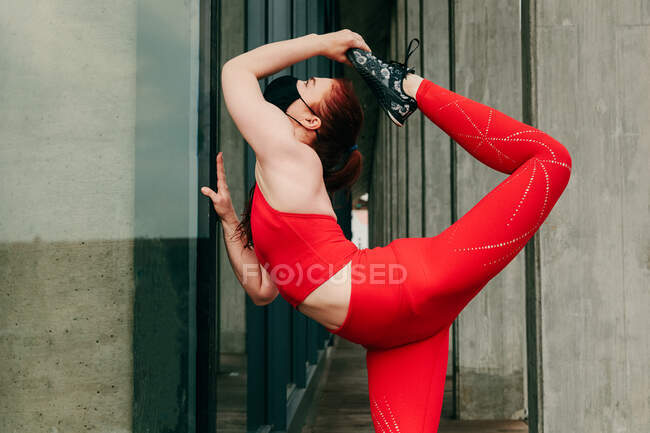 Joven atleta femenina, estirándose en la calle, usando una mascarilla - foto de stock
