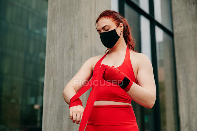 Young female boxer, wrapping wrist in Brooklyn street, with face mask — Stock Photo