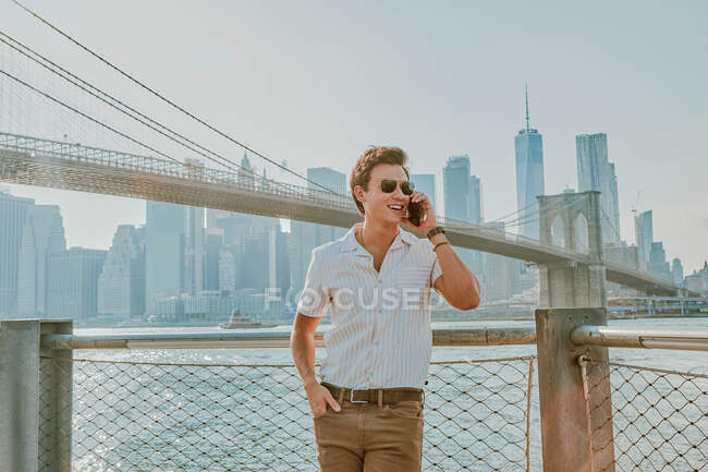 Молодий чоловік стоїть біля річки, розмовляючи по телефону — стокове фото