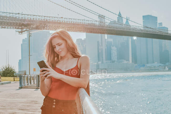 Jovem mulher ao ar livre por rio no telefone. — Fotografia de Stock