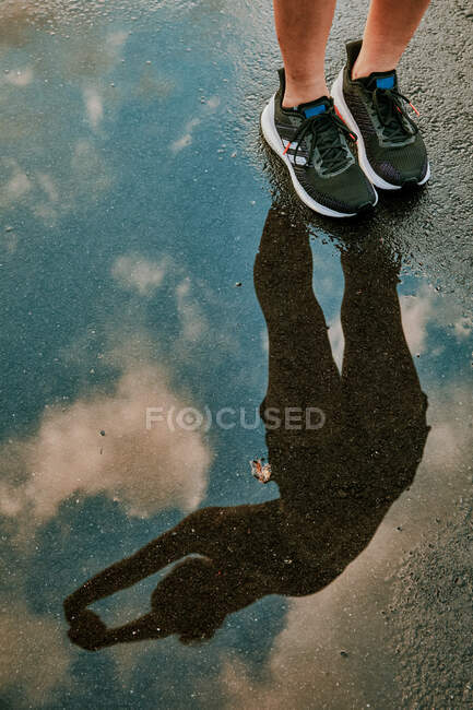 Reflection in water of female athlete stretching. — Stock Photo