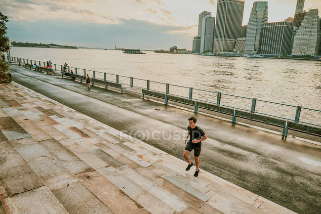 Athlète masculin courant sur les marches pendant le coucher du soleil — Photo de stock