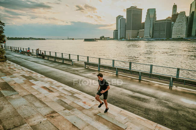 Atleta masculino correndo em degraus durante o pôr do sol — Fotografia de Stock