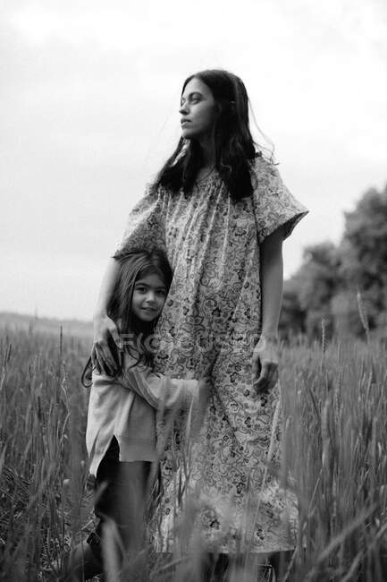 Figlia abbracciare madre in piedi in campo — Foto stock