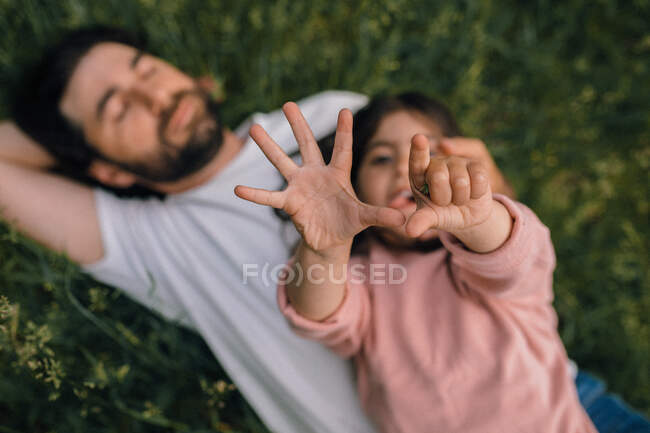 Daughter counting on fingers with dad in field — Stock Photo