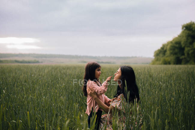 Sorridente madre e figlia e parlando in campo — Foto stock