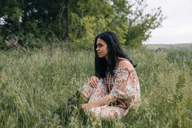 Portrait of woman alone in field thinking — Stock Photo