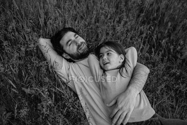 Padre e figlia che posano l'erba sorridendo — Foto stock