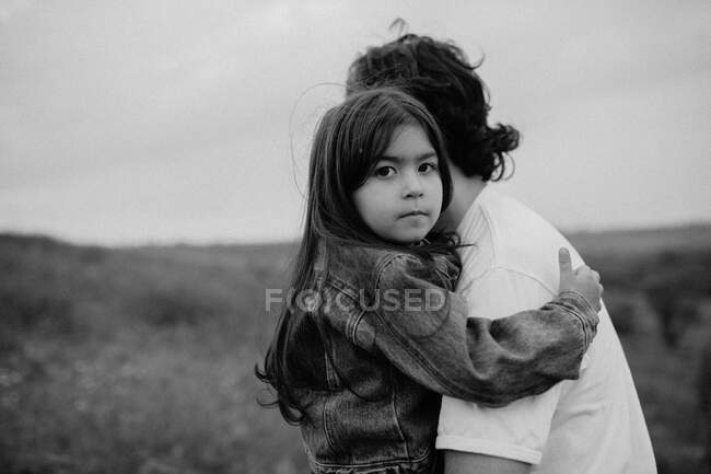 Retrato de niña siendo llevada por padre en el campo - foto de stock