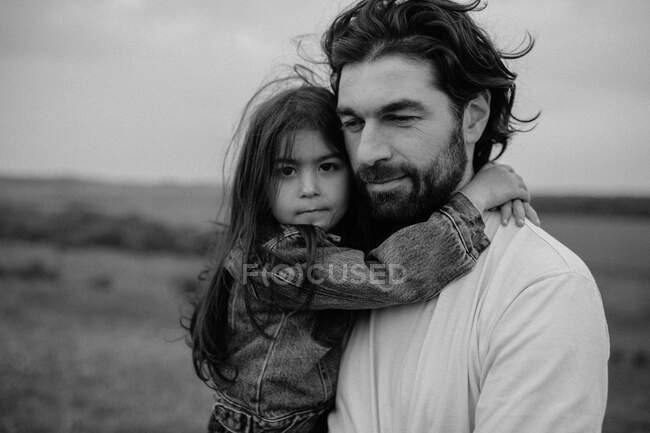 Portrait of girl being carried by father in field — Stock Photo