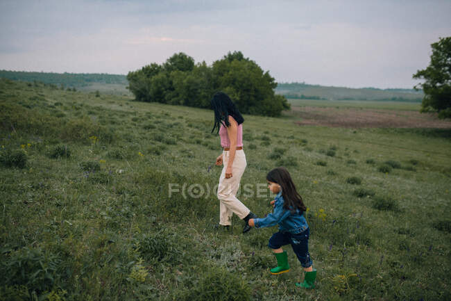 Madre e hija caminando al aire libre en el campo - foto de stock