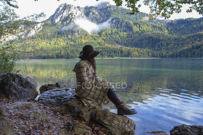 Eine Frau sitzt auf einem Felsen an einem Bergsee in Deutschland — Stockfoto
