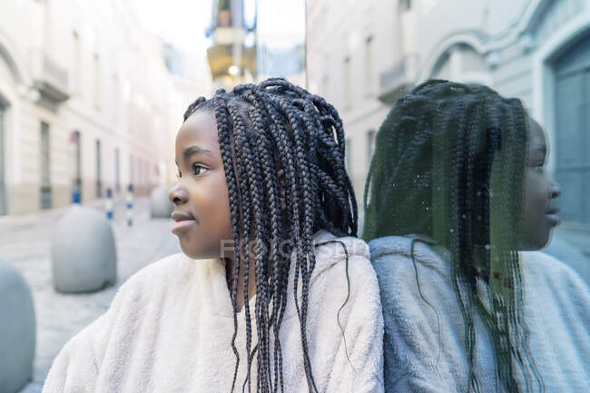 Beautiful african girl with braids on glass wall — Stock Photo
