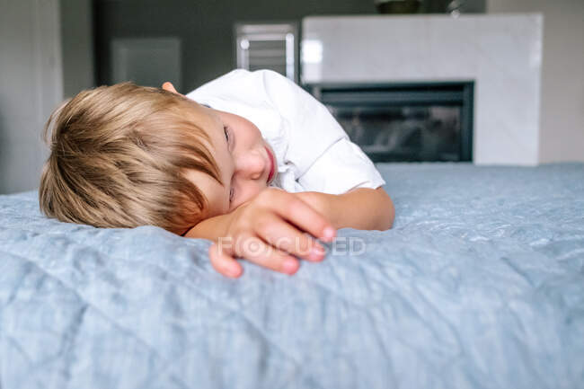 Close up of a young boy laying on parents bed — Stock Photo