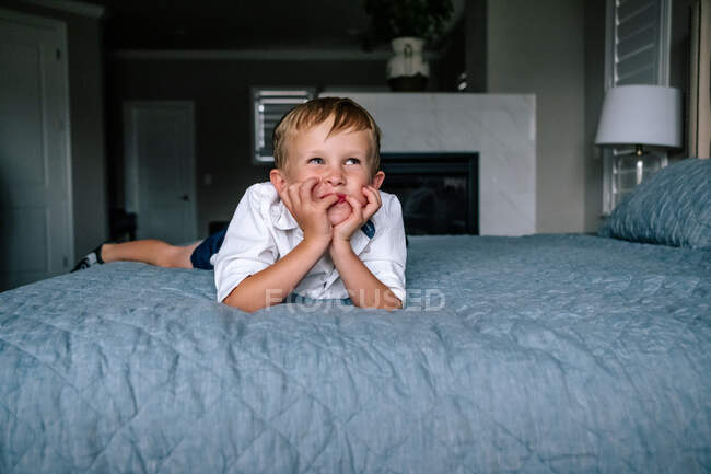 Heureux jeune garçon allongé sur parents lit souriant — Photo de stock