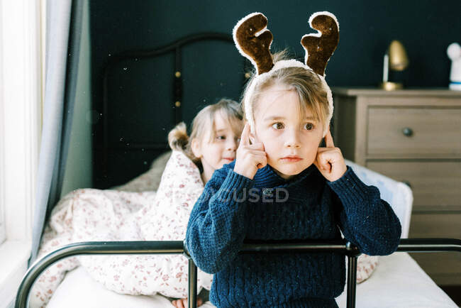 Niño pequeño haciendo una cara seria mientras finge ser un reno - foto de stock