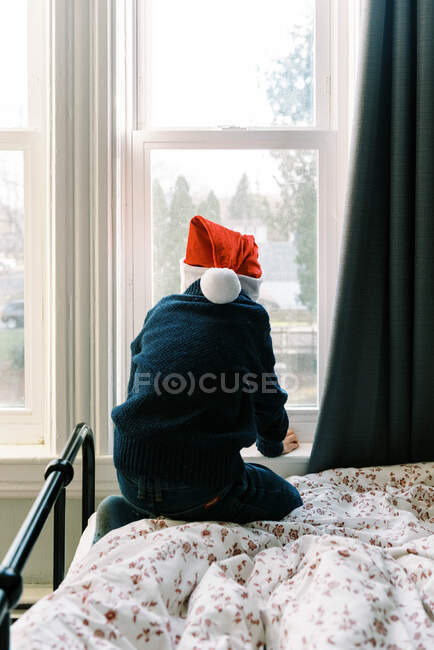 Маленький мальчик смотрит в окно, счастливый ребенок зимой — стоковое фото