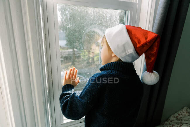 Niño mirando por la ventana, niño feliz en invierno - foto de stock