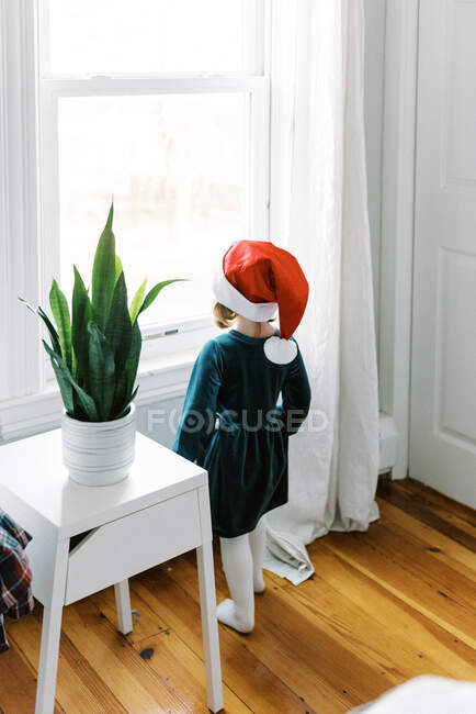 Kleines Mädchen schaut aus Fenster und wartet auf Weihnachtsmann — Stockfoto