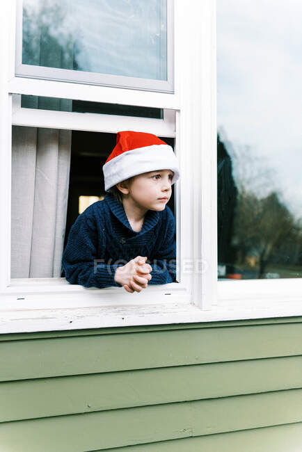 Маленький хлопчик дивиться з вікна, щаслива дитина взимку — стокове фото