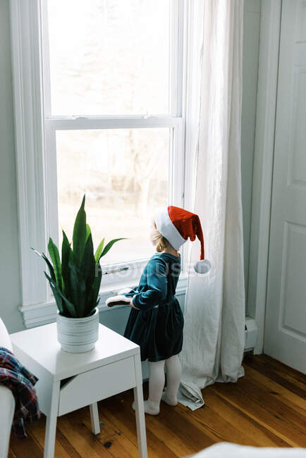 Menina olhando pela janela esperando por cláusula de Papai Noel no Natal — Fotografia de Stock