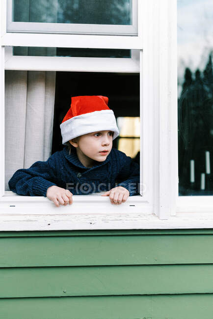 Menino olhando pela janela, criança feliz no inverno — Fotografia de Stock