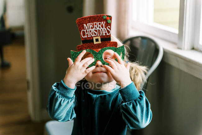 Pequena menina feliz vestindo óculos de Natal bobo no feriado — Fotografia de Stock
