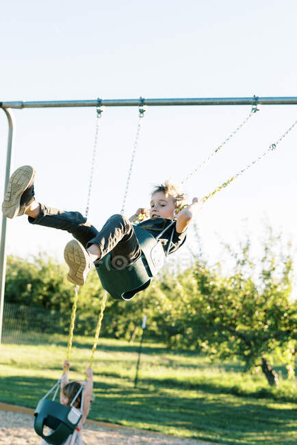 Little boy swinging high on a baby swing and having fun — Stock Photo