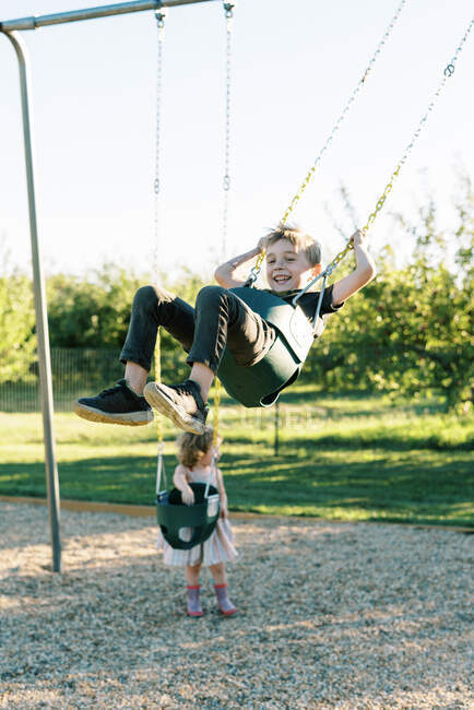 Bambino che oscilla alto su un'altalena per bambini e si diverte — Foto stock