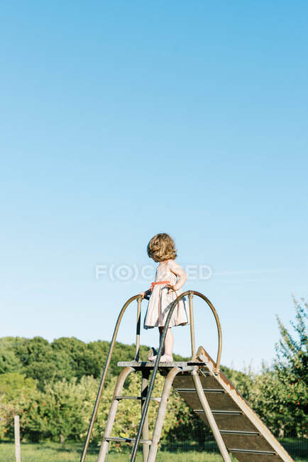 Bambina in piedi su uno scivolo e sentirsi alta e coraggiosa — Foto stock