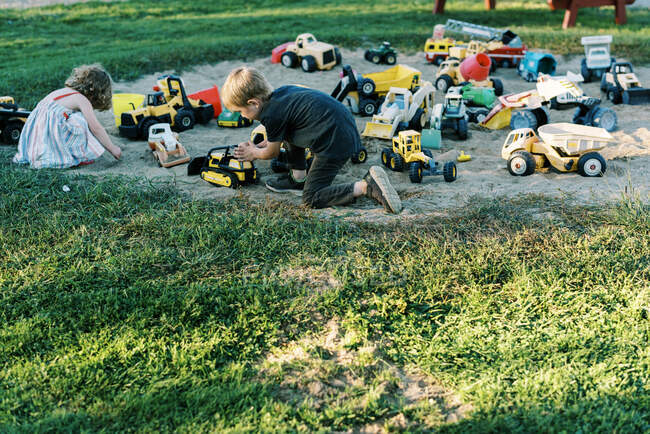 Duas crianças brincando com uma variedade de caminhões em um playground — Fotografia de Stock