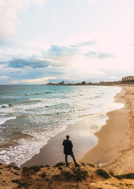 Ansichten eines Mannes von hinten Blick auf einen Strand in einem wolkenverhangenen Himmel — Stockfoto