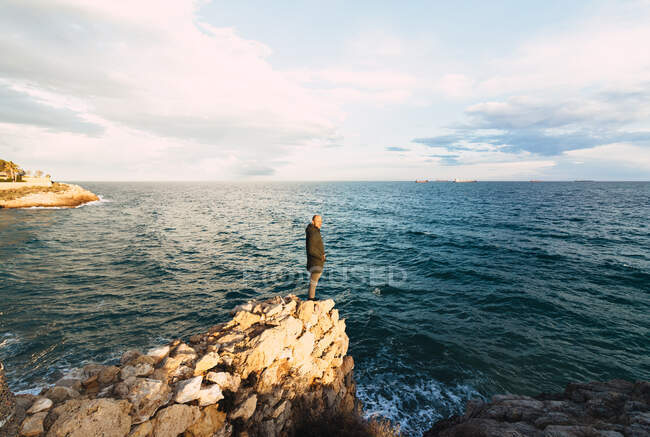 Tiro de um homem no centro de uma paisagem de frente para o mar — Fotografia de Stock
