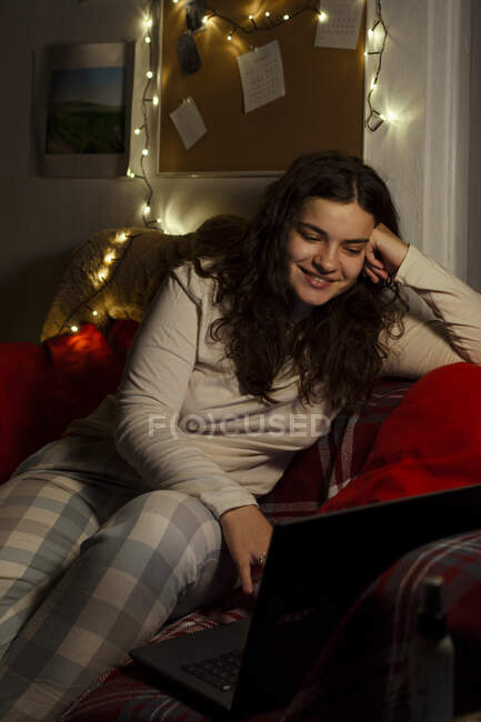 Счастливая девушка делает покупки на Рождество онлайн, оставаясь дома. — стоковое фото