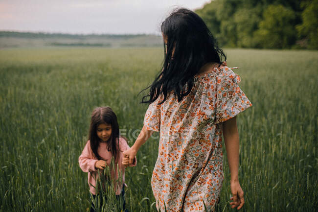 Mère heureuse marchant avec un enfant dans le champ au crépuscule — Photo de stock