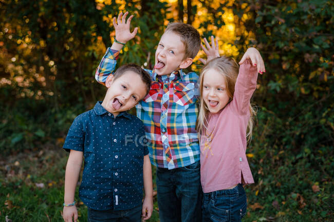 Hermanos hermanos y hermanas siendo tontos durante el retrato familiar - foto de stock