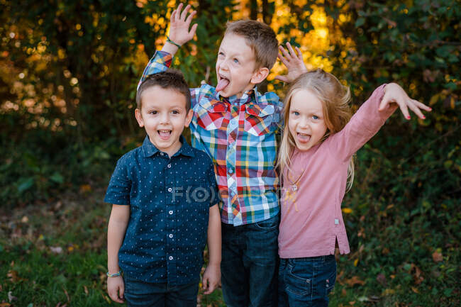 Family brothers and sister making silly faces playing outside — Stock Photo
