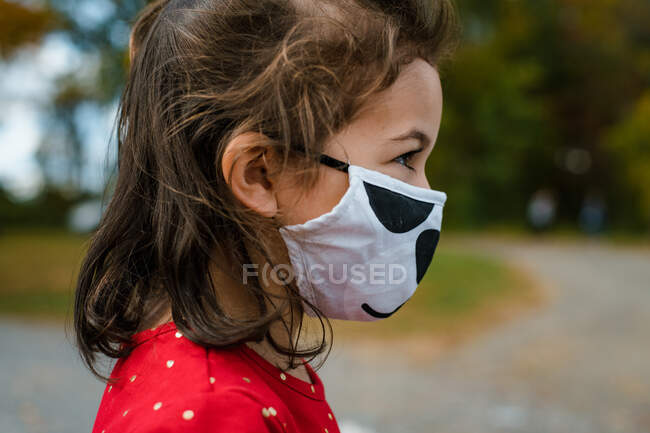 Menina em idade pré-escolar usando máscara protetora fora no outono — Fotografia de Stock